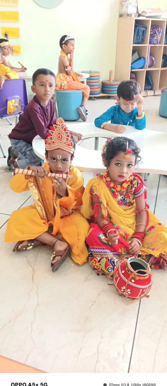Pre-primary students seated as Radha and Krishna with hand-decorated earthen pot