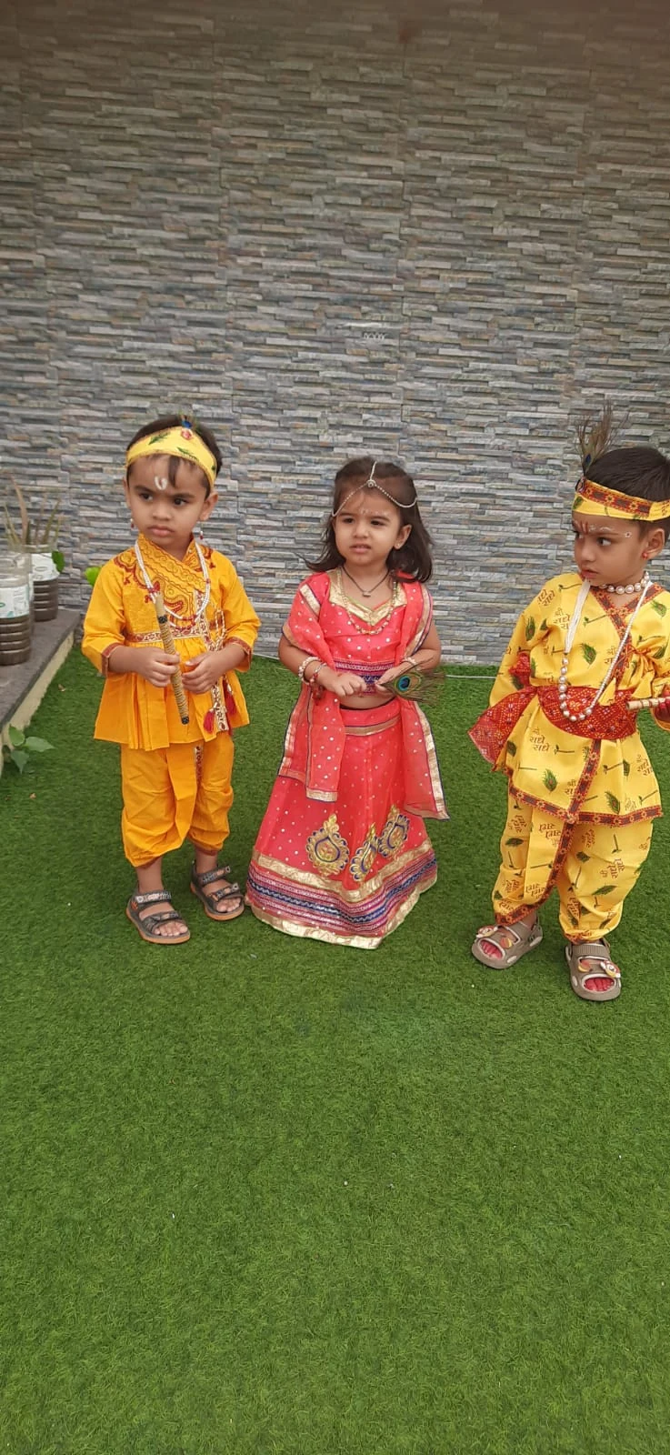 Three young learners in festive cultural attire sharing a happy moment together