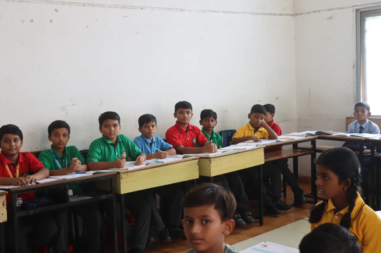 Students walking and gathered in conversation on the green school grounds of Jet Kids in Pusad